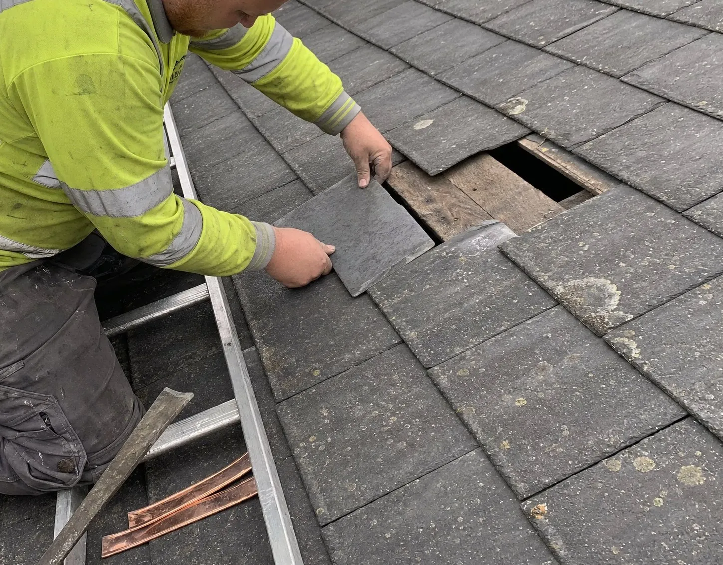 Jamie fitting a replacement slate where storm damage has exposed the battens