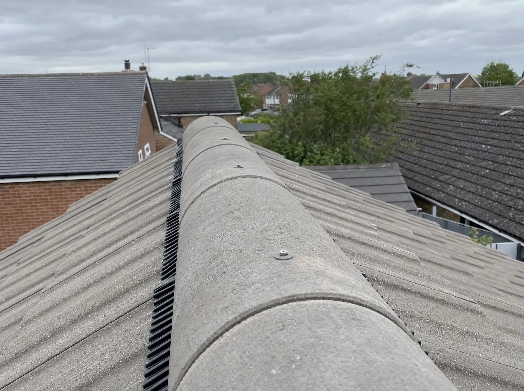 A finished dry ridge, each ridge tile screwed down over a ventilated ridge roll