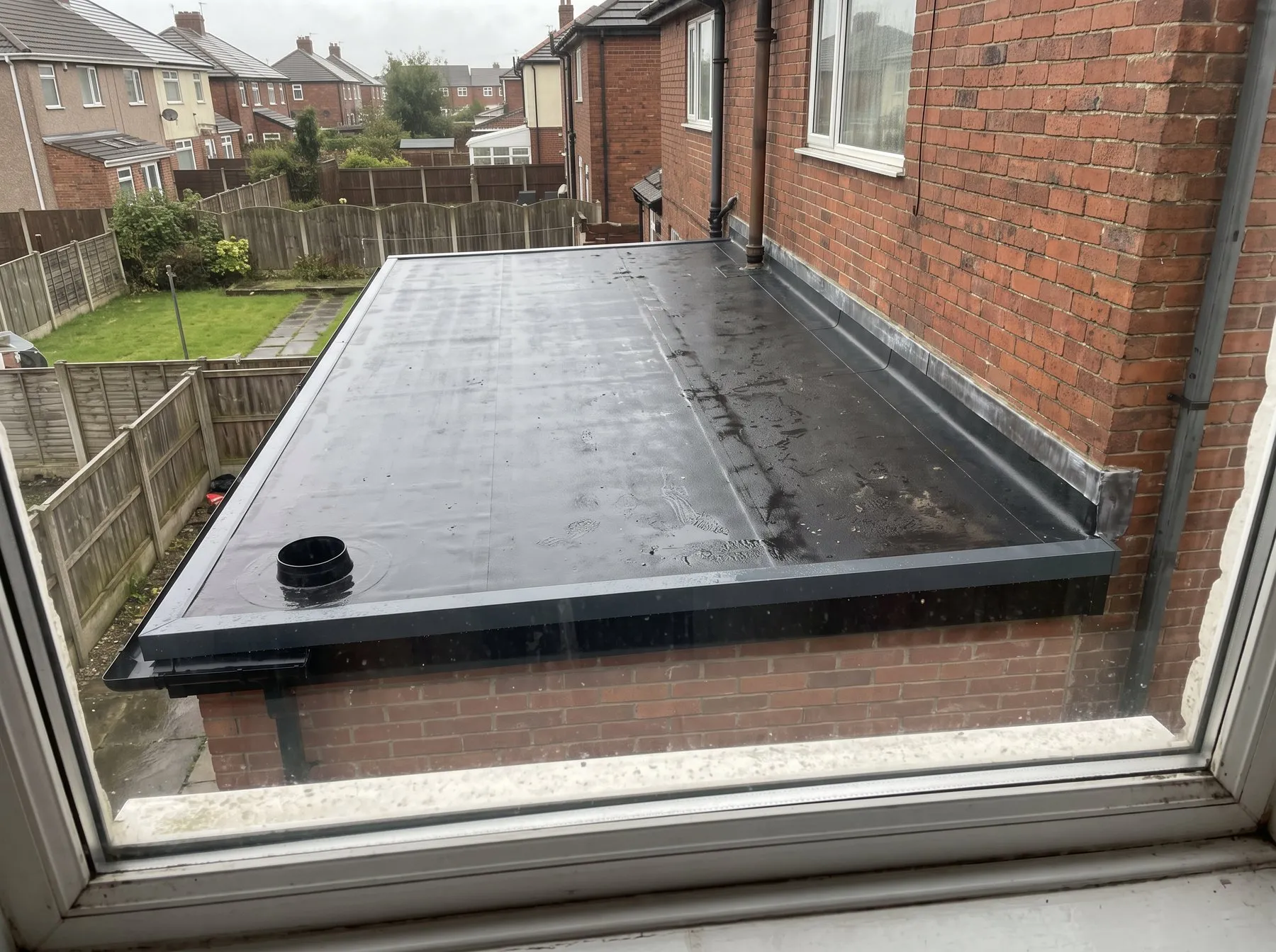 A finished rubber flat roof on a rear extension with new trims and an outlet