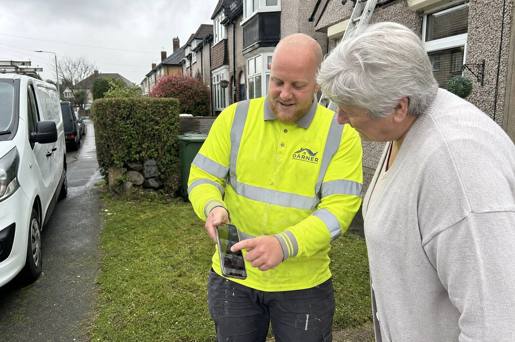 Jamie showing a homeowner the photos of her roof on his phone