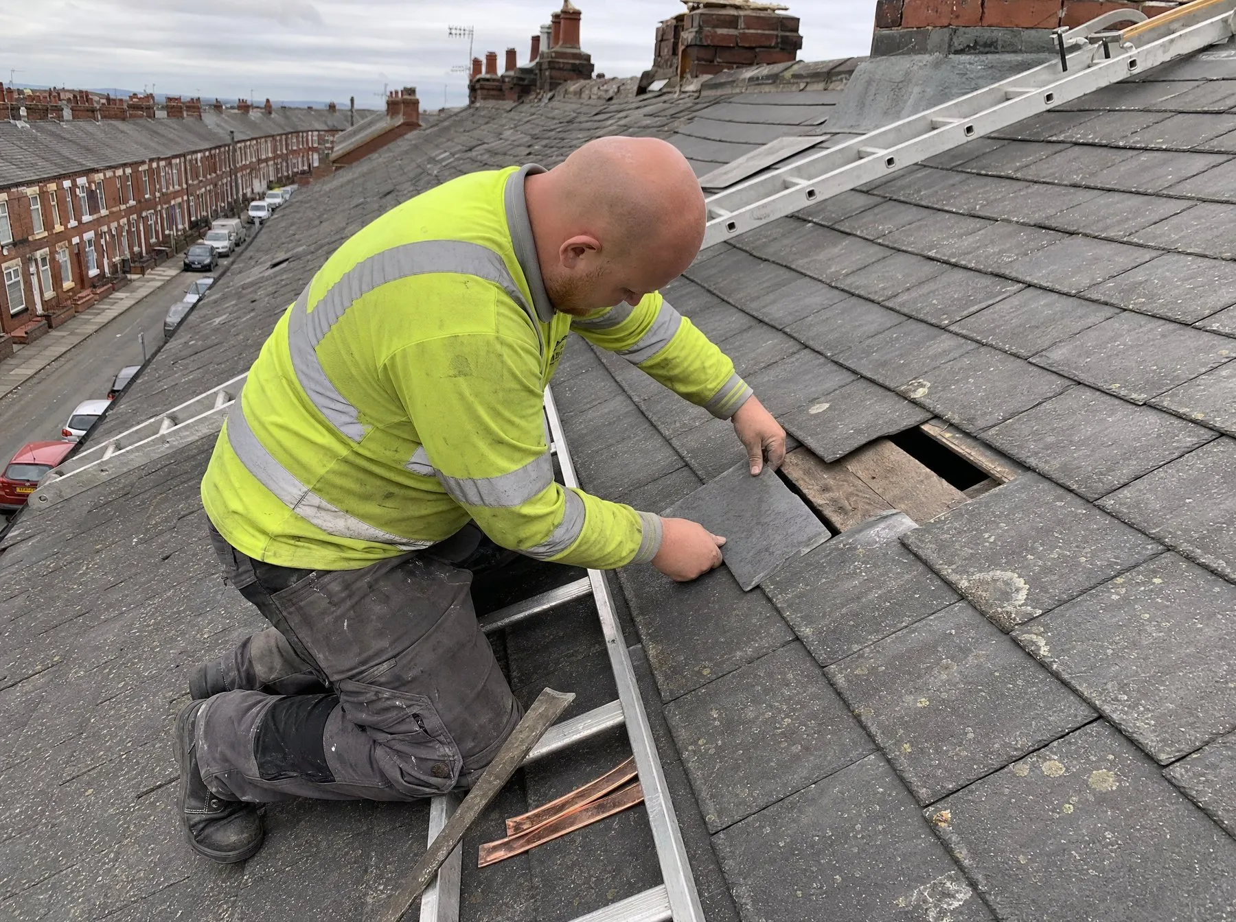 Jamie replacing broken slates from a roof ladder on a terraced roof